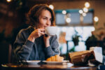 Kobieta pijąca kawę z białej filiżanki.